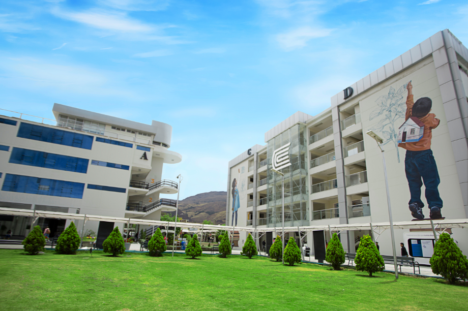 Vista aérea del campus universitario mostrando edificios modernos, áreas verdes y senderos accesibles con rampas